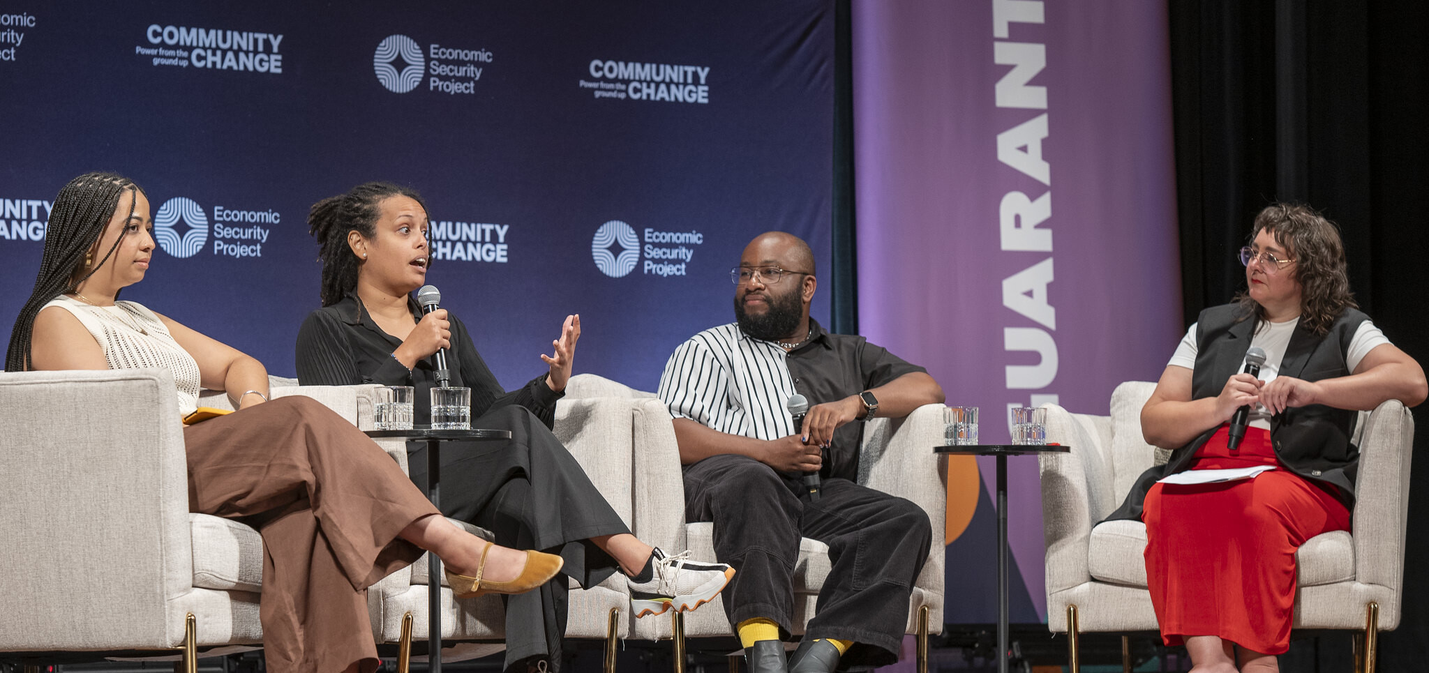 Maura Cuffie-Peterson, Ricardo Beaird, Claudia Maturell and moderator Cara Rose Defabio sitting on chairs on a stage at the Guaranteed Income Now Conference. Photo by Economic Security Project